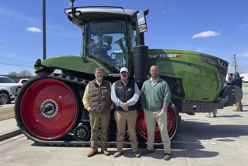 Leadership team Delta Ag Equipment standing in front of Fendt tractors at the dealership.