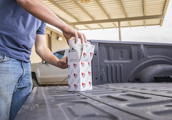 Person placing AGCO Parts oil filters on the tailgate of a pickup truck.